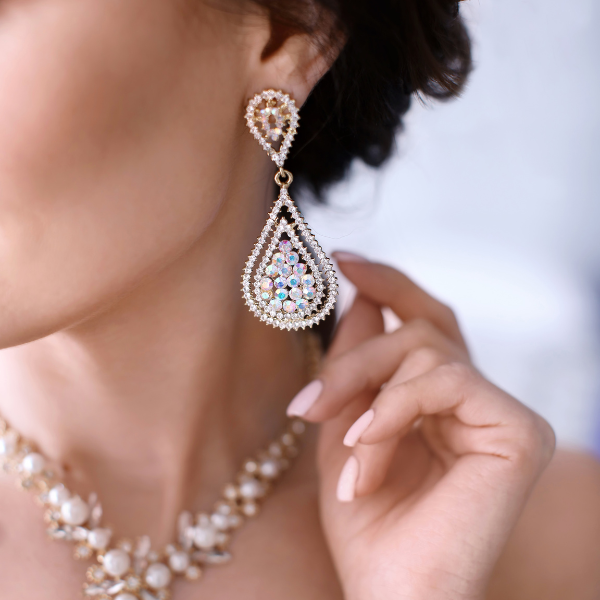Pear-shaped chandelier drop earrings worn with a pearl necklace