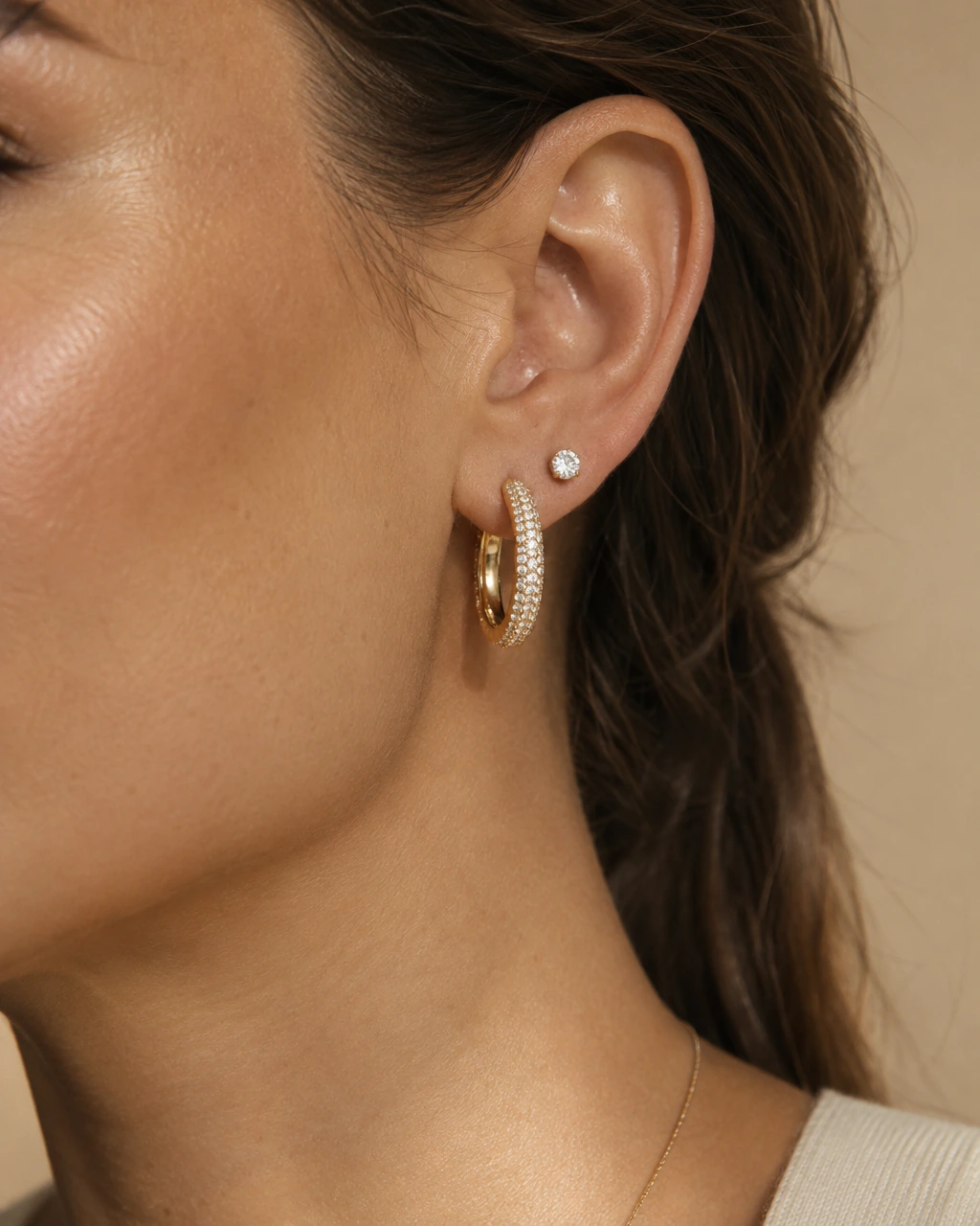 A pavé diamond hoop and a diamond stud earring in yellow gold, worn